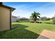 Spacious backyard overlooking a pond with lush green lawn and tropical palm tree at 351 Hope Bay Loop, Apollo Beach, FL 33572