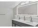 Bathroom with a double sink vanity, a large, illuminated mirror, and modern fixtures at 4520 Pine Hollow Dr, Tampa, FL 33624