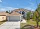 Charming two-story home featuring an attached garage, arched window, neutral color, and mature landscaping at 5337 Treig Ln, Wesley Chapel, FL 33545