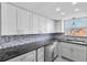 Bright, renovated kitchen with white cabinetry, granite countertops, and stainless steel appliances at 5440 Quist Dr, Port Richey, FL 34668