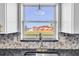 Bright kitchen sink features a modern faucet, granite counters, stylish backsplash and a large window with neighborhood views at 5440 Quist Dr, Port Richey, FL 34668