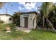 This is a small storage shed in the backyard with a gray door, plants, and exterior hanging planters at 5440 Quist Dr, Port Richey, FL 34668