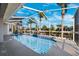 A screened-in pool with clear blue water sits beside a canal lined with tropical palm trees on a sunny day at 5815 Dory Way, Tampa, FL 33615