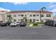 Condominium exterior with stucco walls, red tile roof, palm trees, and ample parking spaces at 6077 Bahia Del Mar Blvd # 119, St Petersburg, FL 33715