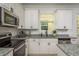 Bright kitchen featuring white cabinets, stainless steel appliances, granite counters and light wood flooring at 637 Jetstar Ln, Oldsmar, FL 34677
