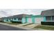 Street view of a row of tidy turquoise townhomes, each with a garage, gray roof, and landscaped front yard at 7060 Lafayette St # 7060, Pinellas Park, FL 33781