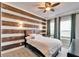 Comfortable bedroom with a wood accent wall, ceiling fan, and natural light at 8005 Cypress Crossing Ct, Tampa, FL 33647