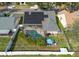 Aerial view of backyard oasis featuring a screened pool, solar panels, mature landscaping, and patio at 9415 Pebble Glen Ave, Tampa, FL 33647