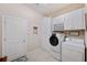 Well-lit laundry room featuring front-load washer and dryer, ample cabinet space, and tile flooring at 11720 Bitola Dr, Odessa, FL 33556