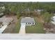 Aerial view of single-story home shows its neutral paint, and a two-car garage surrounded by mature trees and a well-maintained lawn at 12341 Filbert Rd, Brooksville, FL 34614