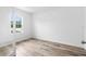 Bright bedroom features a large window, wood-look floors, white walls, and a door leading to another room at 12341 Filbert Rd, Weeki Wachee, FL 34614
