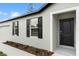 This home's exterior shows classic black shutters, neutral paint, and a front door with a mulch bed below the windows at 12341 Filbert Rd, Weeki Wachee, FL 34614