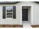 The home's front door is framed by a white border, with classic black shutters, and neutral paint at 12341 Filbert Rd, Weeki Wachee, FL 34614
