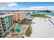 An aerial view showcasing the condo building, pool area, tiki huts, and proximity to the beach at 12924 Gulf Blvd # 503, Madeira Beach, FL 33708