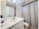 Bright bathroom features a white vanity, a mirror, and toilet with a shower and curtain at 12924 Gulf Blvd # 503, Madeira Beach, FL 33708