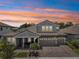 Striking exterior of a two-story home, showcasing a well-maintained lawn, brick driveway, and spacious three-car garage at 13069 Paddock Wood Pl, Riverview, FL 33579