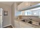 Well-lit kitchen featuring stainless steel sink, white cabinets, and neutral countertop at 1400 Gandy N Blvd # 502, St Petersburg, FL 33702