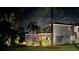 Night view of a beautiful screened lanai and meticulously maintained backyard surrounded by mature trees at 15702 Muirfield Dr, Odessa, FL 33556