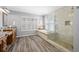 Bathroom featuring a glass enclosed shower, soaking tub, wood-look floors, and shuttered windows at 15702 Muirfield Dr, Odessa, FL 33556