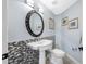 Powder room with pedestal sink, decorative mirror, stylish lighting, and mosaic tile accent wall at 15702 Muirfield Dr, Odessa, FL 33556