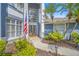 Inviting home entrance with double doors, an American flag, manicured landscaping, and palm trees at 15702 Muirfield Dr, Odessa, FL 33556