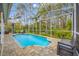 Backyard screened-in pool featuring paver deck, lush landscaping, and a serene outdoor oasis at 15702 Muirfield Dr, Odessa, FL 33556