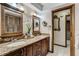 Bathroom featuring dual sinks, granite counters, wood cabinetry, decorative mirrors, and tile flooring at 1672 Winding Creek Rd, Dunedin, FL 34698