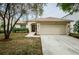 Charming single-story home featuring a manicured front yard, mature tree, and a two-car garage at 18186 Sandy Pointe Dr, Tampa, FL 33647