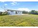 Back exterior view of the house with a kidney-shaped pool and a large grassy yard at 184 Garden Nw Ave, Port Charlotte, FL 33952