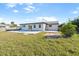 Back exterior view of the home with a kidney-shaped pool and a large grassy yard at 184 Garden Nw Ave, Port Charlotte, FL 33952