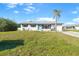 Charming single-story home featuring a turquoise door, black shutters, and a neatly landscaped front yard at 184 Garden Nw Ave, Port Charlotte, FL 33952