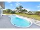 Backyard featuring a kidney-shaped pool, surrounded by a concrete patio and green grass at 184 Garden Nw Ave, Port Charlotte, FL 33952