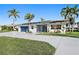 Charming one-story home with a blue garage door, impact windows, and well-manicured lawn and landscaping at 1984 Kansas Ne Ave, St Petersburg, FL 33703