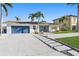 Attractive one-story home with lush landscaping, blue garage door, and sidewalk leading to the front door at 1984 Kansas Ne Ave, St Petersburg, FL 33703