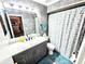 The full bathroom features a granite vanity, a large mirror and colorful shower curtain at 1988 Georgia S Cir, Clearwater, FL 33760