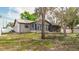 View of the home's backyard with an exposed foundation and mature shade trees at 2427 Comerwood Dr, Spring Hill, FL 34609