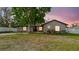 Charming single-story home showcasing a well-maintained front yard and mature tree at dusk at 2427 Comerwood Dr, Spring Hill, FL 34609
