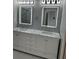A bathroom featuring a dual vanity sink, updated lighting, and a glass door shower at 2900 W Azeele St # H, Tampa, FL 33609