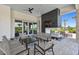 Covered patio with comfortable seating around a modern fireplace and a flat screen TV at 4228 Isonzo Way, Wesley Chapel, FL 33543