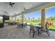 Covered patio with tables and seating and a view to the yard and palm trees at 4228 Isonzo Way, Wesley Chapel, FL 33543