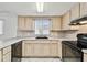 Traditional kitchen with white tile flooring, black appliances, and wood cabinets at 5407 Embassy Ave, New Port Richey, FL 34652