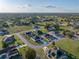 Aerial view of a home in a residential neighborhood surrounded by green spaces, near a body of water with clear blue skies at 5433 Chestnut Ridge Rd, Dade City, FL 33523