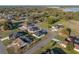 Aerial view of a residential property with a dark roof surrounded by greenery, in a suburban neighborhood with a water feature at 5433 Chestnut Ridge Rd, Dade City, FL 33523