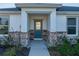 Close-up of a stylish entrance with a teal front door, stone accents, and manicured landscaping at 5433 Chestnut Ridge Rd, Dade City, FL 33523