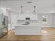 Bright kitchen featuring white cabinets, stainless steel appliances, a large island, and stylish pendant lighting at 5433 Chestnut Ridge Rd, Dade City, FL 33523