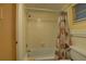 Bright bathroom with a tiled shower-tub combination featuring a shower curtain with a seashell pattern and a small window at 6310 Midnight Pass Rd # 204N, Sarasota, FL 34242