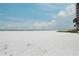 Expansive white sand beach under a blue sky, adjacent to lush vegetation and a high-rise building at 6310 Midnight Pass Rd # 204N, Sarasota, FL 34242