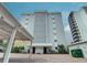 Low-angle shot of condo building with covered parking, lush landscaping, and building number sign at 6310 Midnight Pass Rd # 204N, Sarasota, FL 34242