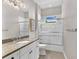 Well-lit bathroom featuring white cabinets, granite countertop, and tiled shower at 7233 Whittlebury Trl, Bradenton, FL 34202