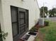 Back exterior view showcasing the screened in lanai door, AC unit, clean lawn and the overall building appearance at 8055 Picketts Ct # 1, Weeki Wachee, FL 34613